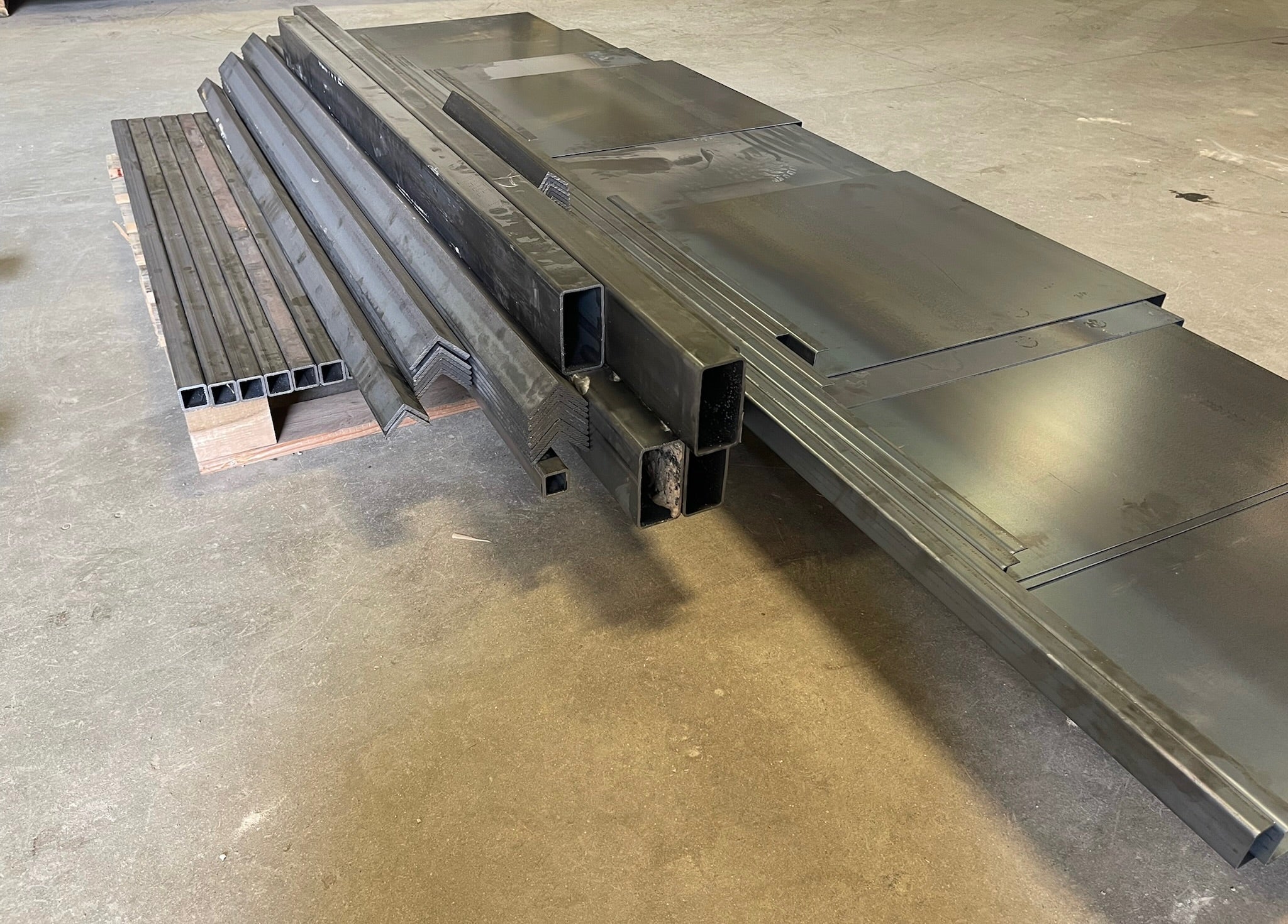 Stack of metal sheets and profiles on a concrete floor